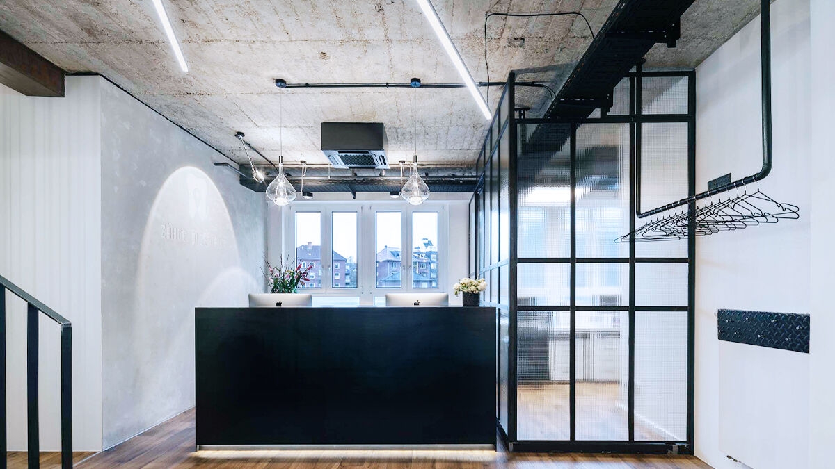Entrance area of the practice Zähne im Zentrum in Münster. Open space with the clear lines of the reception desk and ceiling lighting.