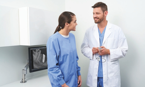 Hygienist and doctor talking and holding Xios AE sensor in front of intraoral implant X-ray