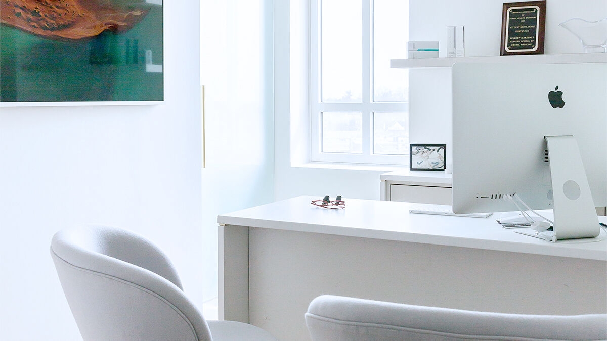 Consultation room in a dental practice with chairs in front of a desk.