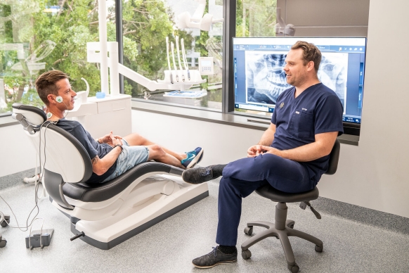Dentist Dr. Patrick Martin in his clinic talking to a patient.