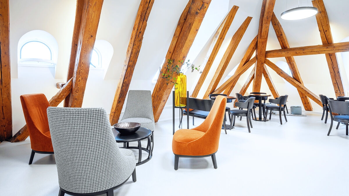 Waiting room of a dental practice. The visible wooden beam look is part of the interior design in soft earth tones.