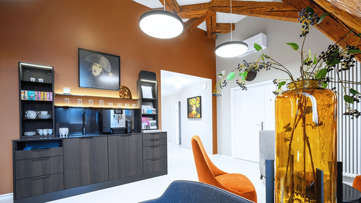 Waiting room of a dental practice with stylish interior design in earth tones, wooden beam look and a coffee bar.