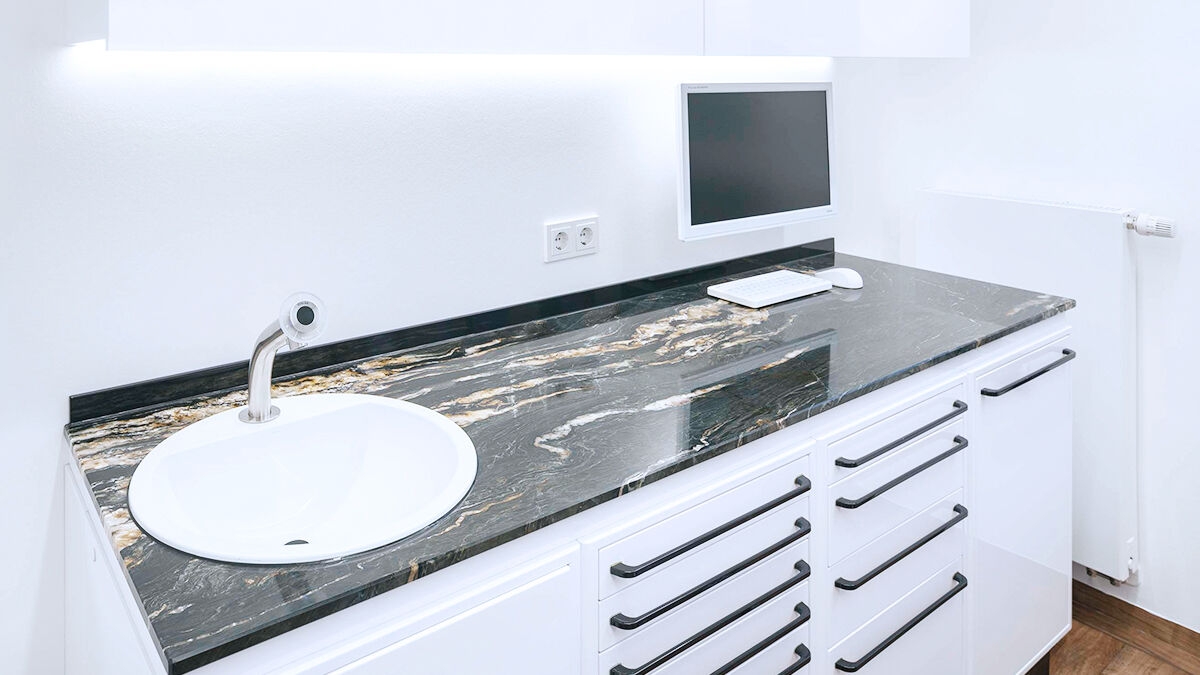Dark stone counter top with sink and drawers inside a treatment room of the Zähne im Zentrum practice in Münster.