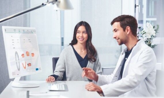 Patient consultation with Uniscan, male dentist and female patient watching screen